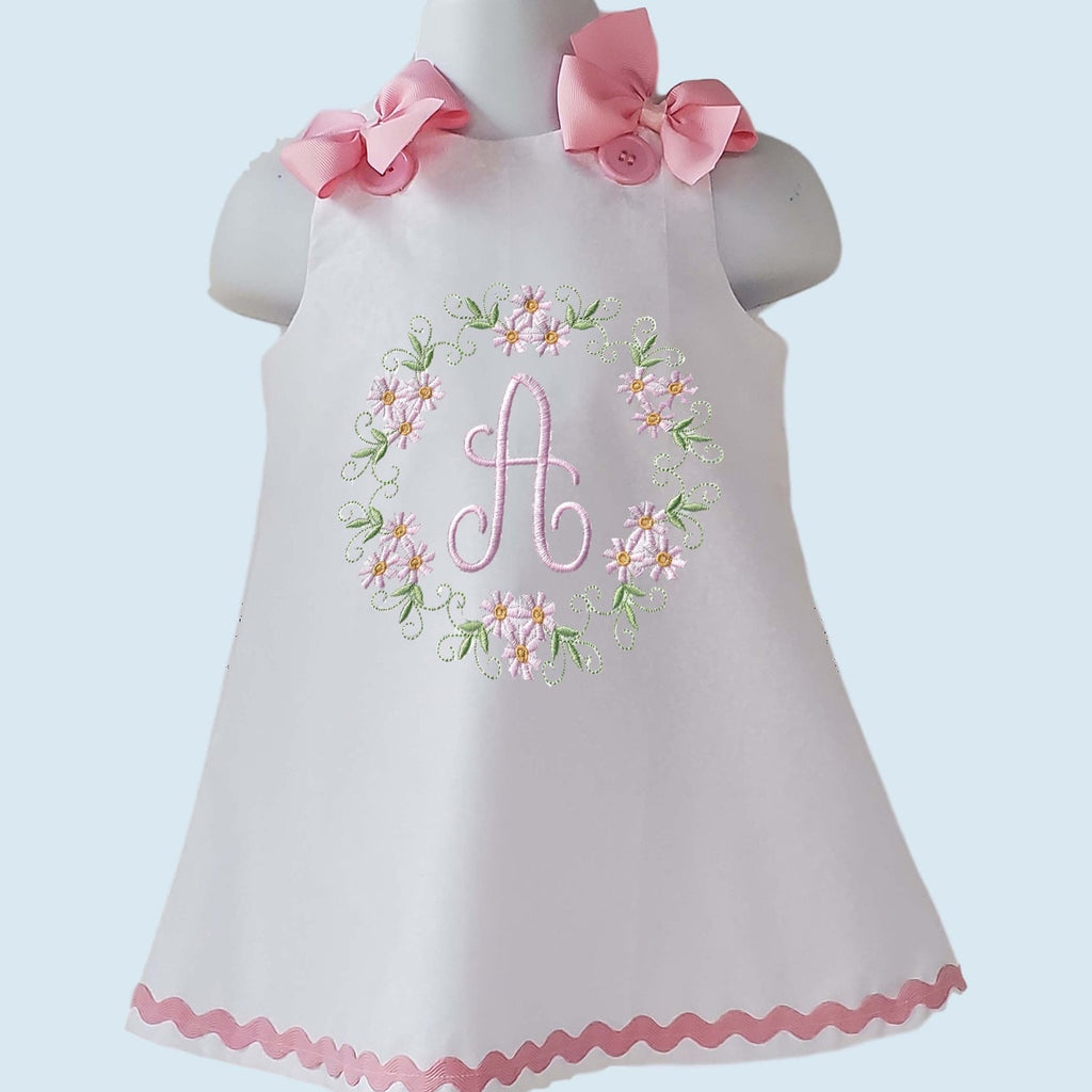 Children's dress with floral embroidery and pink accents on a light blue background