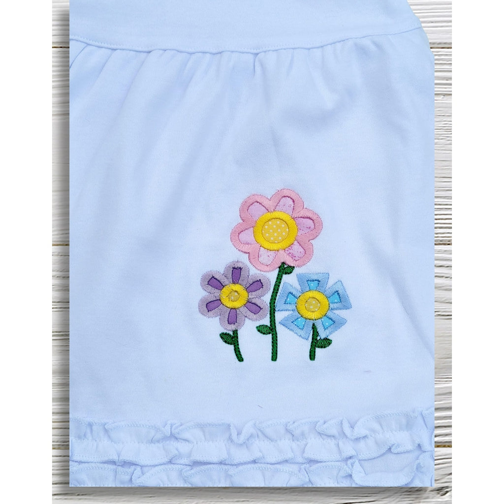 Light blue fabric with colorful flower appliqués on a wooden surface