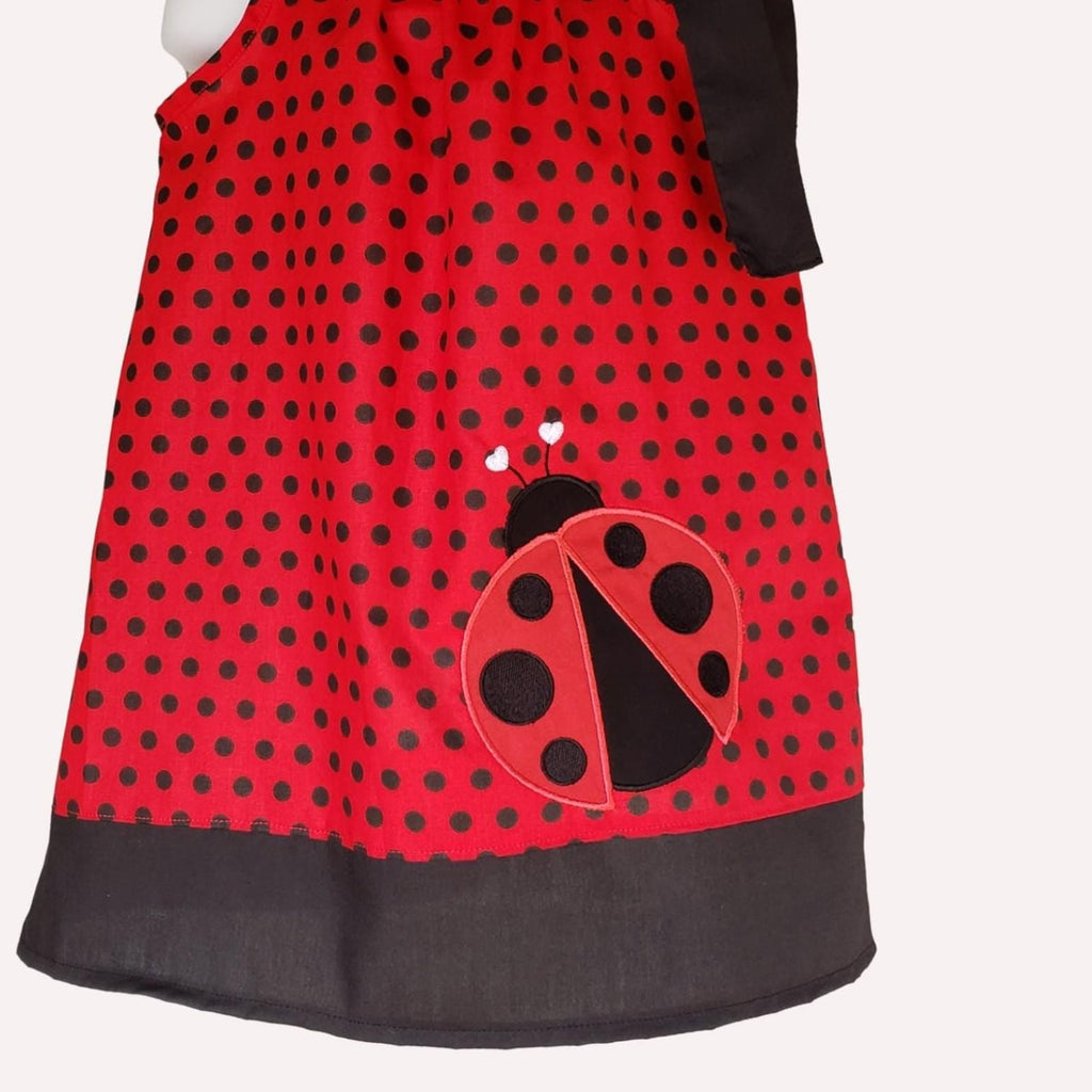 Red apron with black polka dots and a ladybug design on a white background