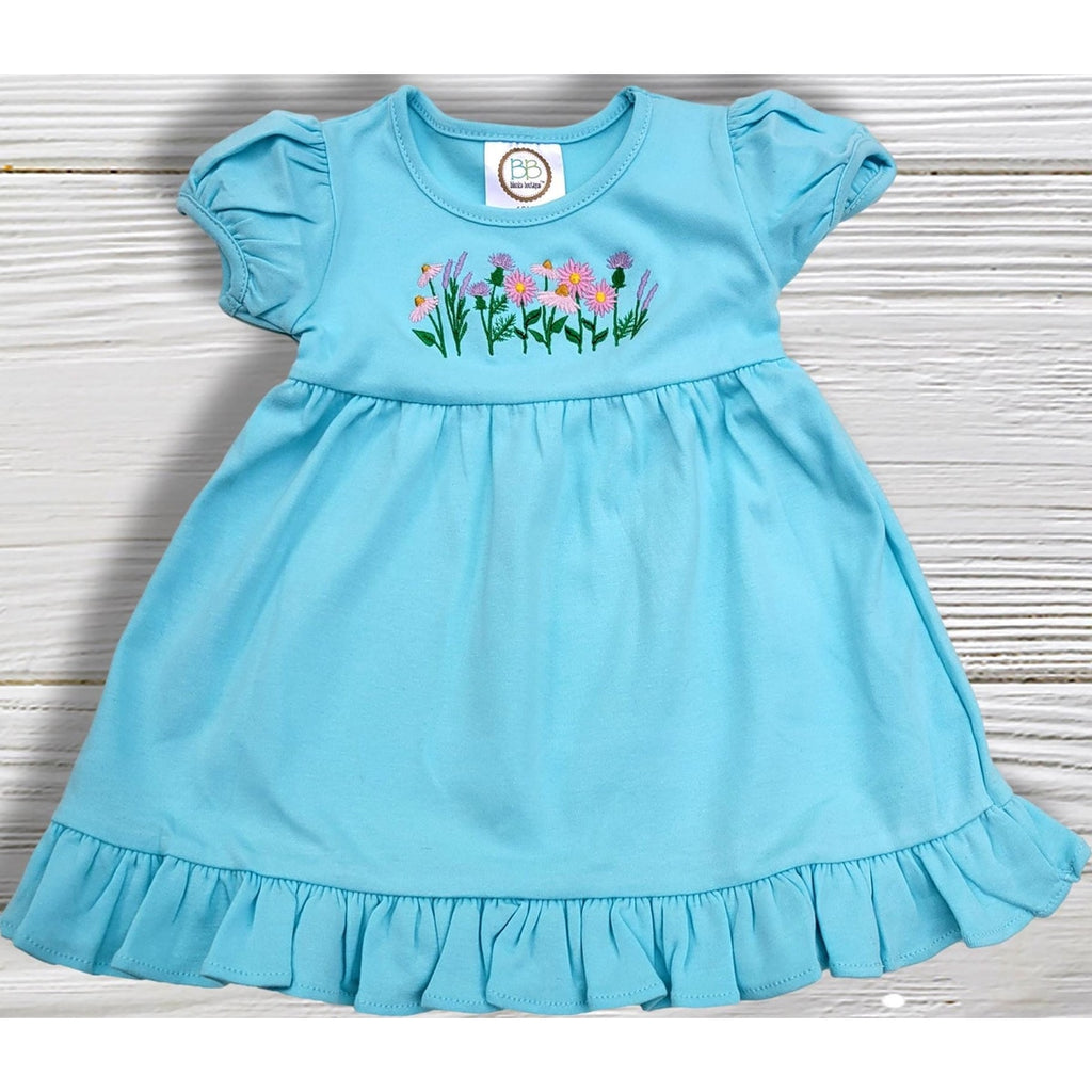 Light blue dress with floral embroidery on a wooden surface