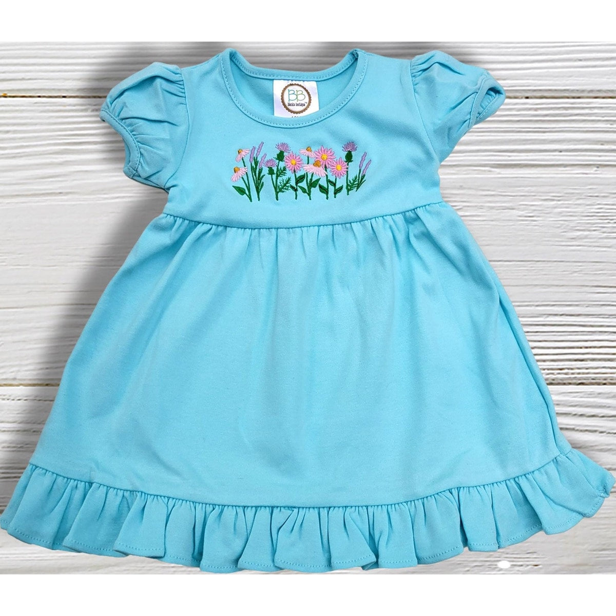 Light blue dress with floral embroidery on a wooden surface
