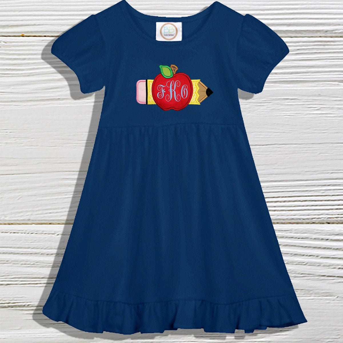 Navy blue dress with a colorful pencil and apple design on a wooden surface