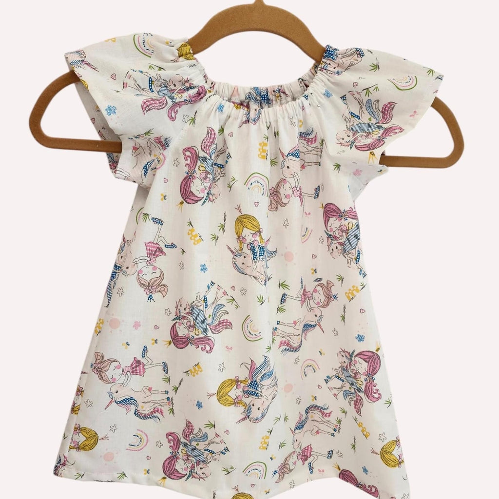 Children's dress with unicorn pattern on a hanger against a white background