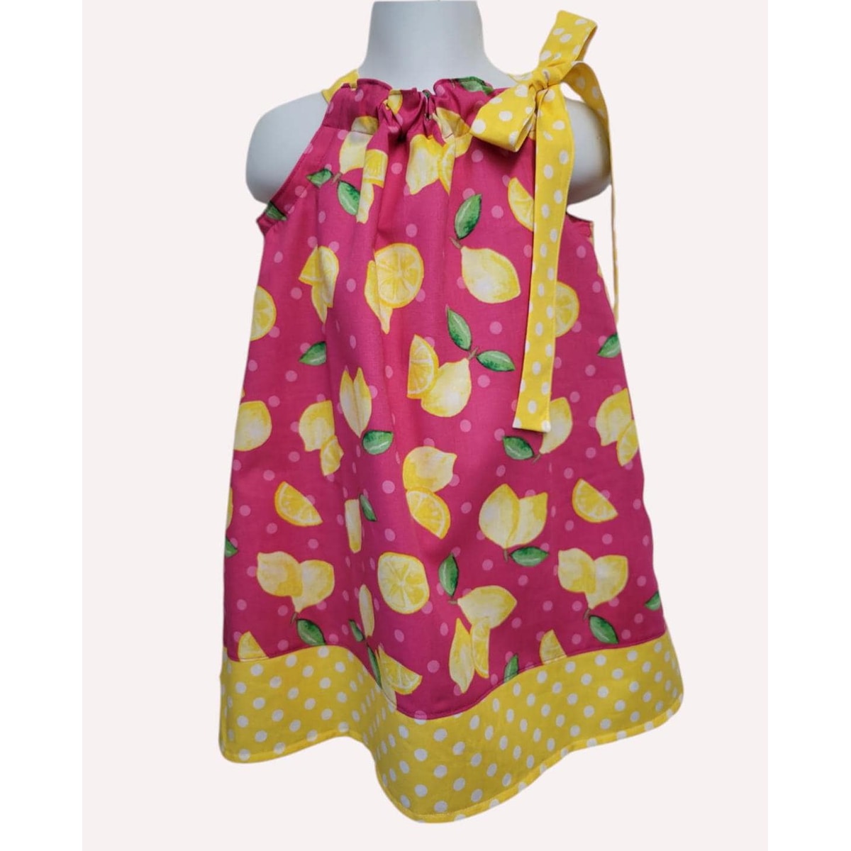 Pink dress with lemon pattern on a mannequin against a white background