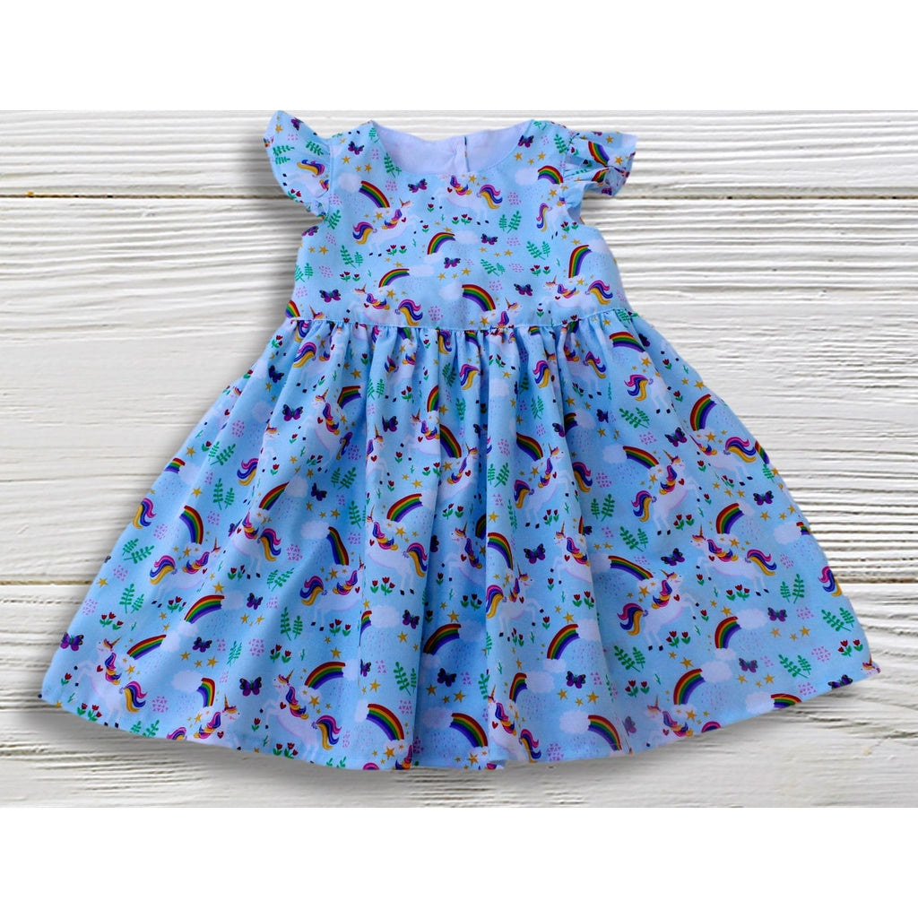 Children's dress with rainbow and unicorn pattern on a wooden surface