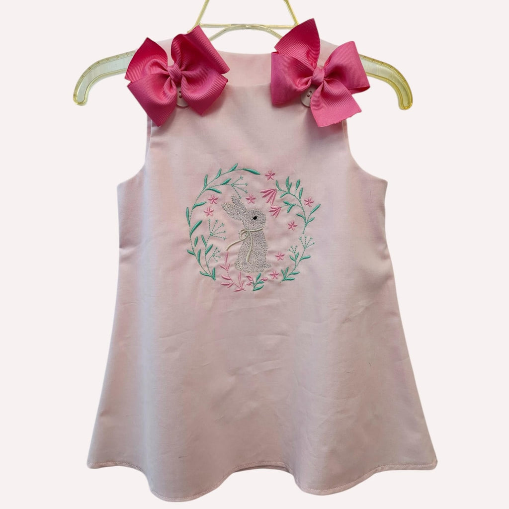 Pink sleeveless dress with floral embroidery and large pink bows on a white background