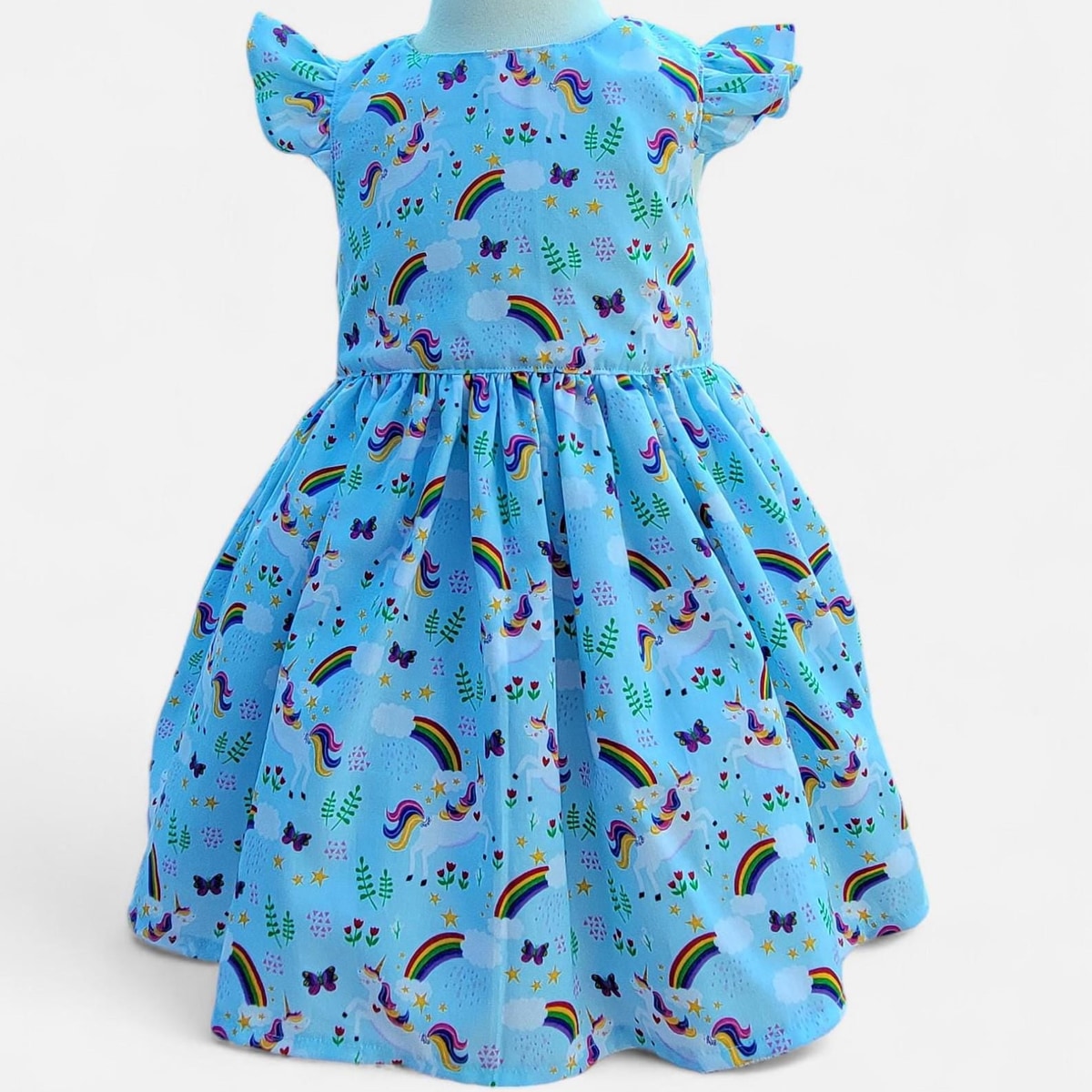 Children's dress with rainbow and unicorn pattern on a light blue background