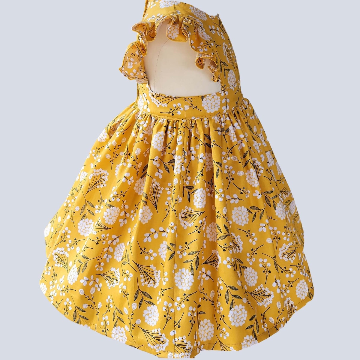 Yellow floral dress on a mannequin against a light gray background