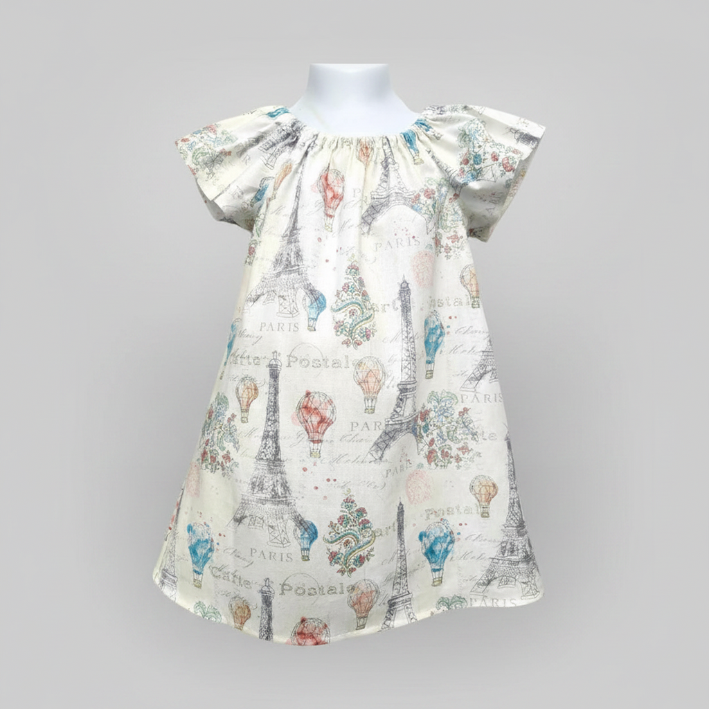 Children's dress with Paris-themed print on a mannequin against a gray background