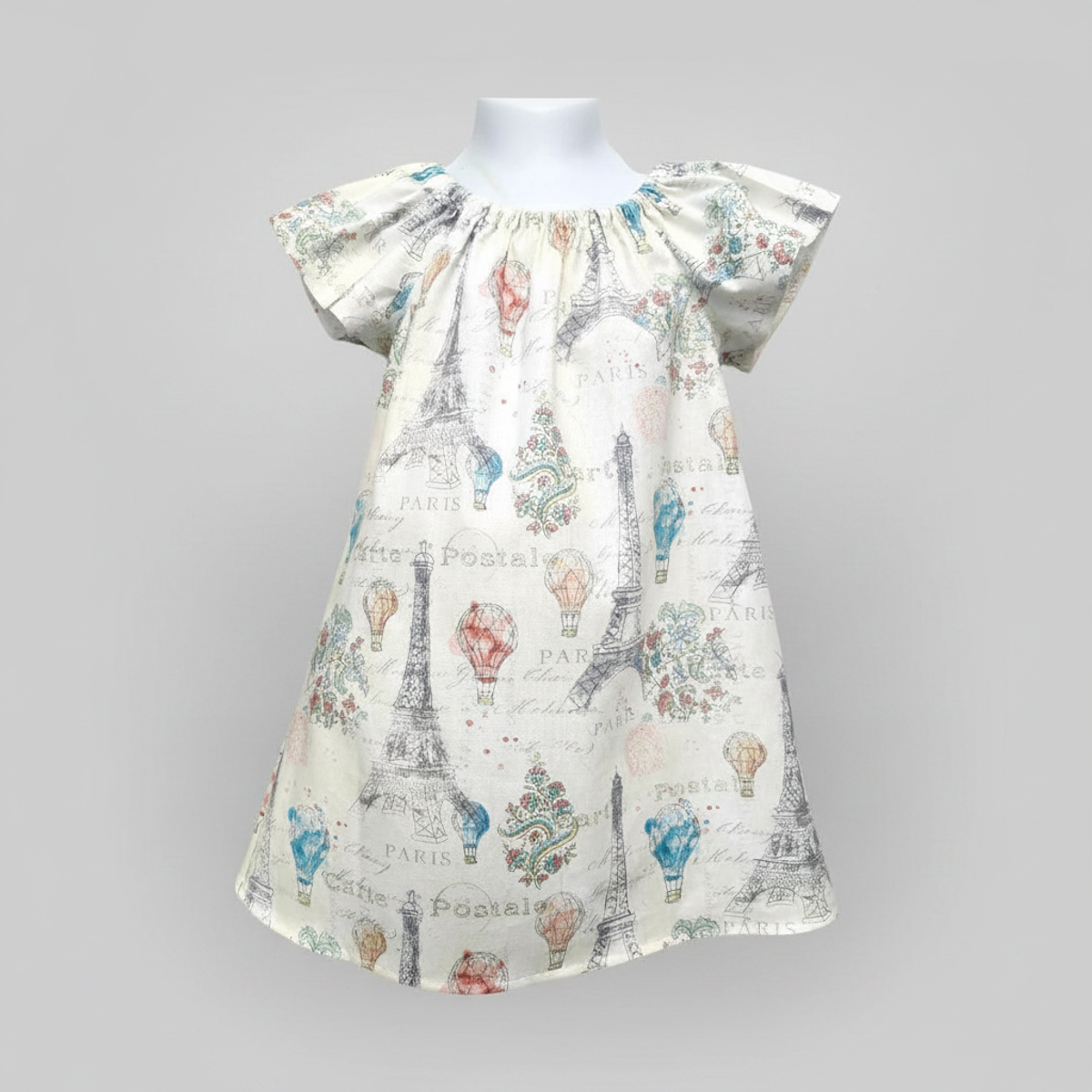 Children's dress with Paris-themed print on a mannequin against a gray background