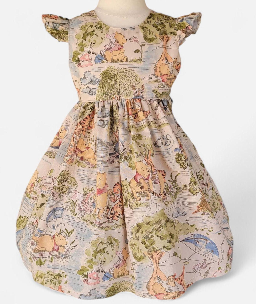 Children's dress with Winnie the Pooh pattern on a mannequin against a white background