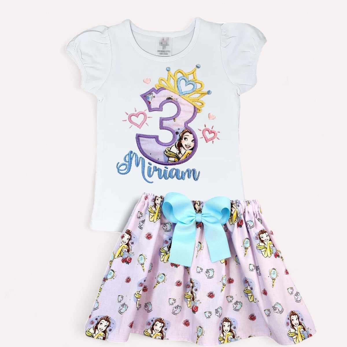 Children's outfit with a white top and pink skirt featuring princess designs and the number 3.