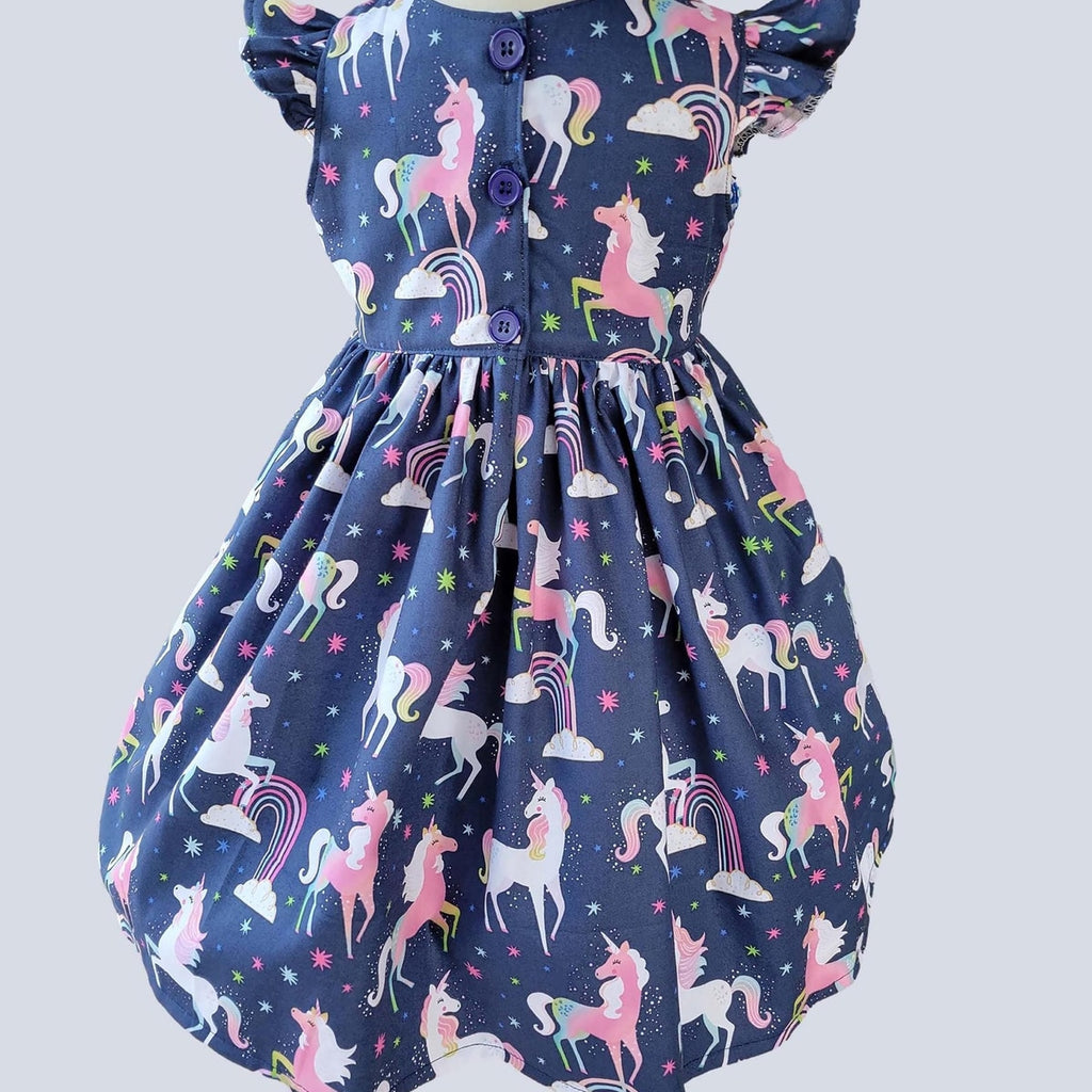 Children's dress with unicorn pattern on a plain background
