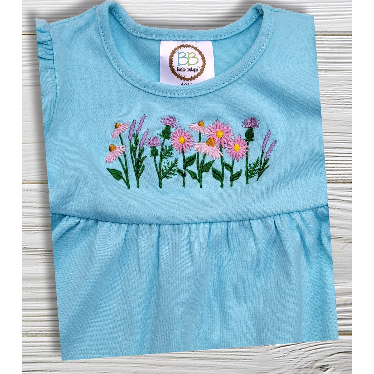 Light blue dress with floral embroidery on a wooden surface