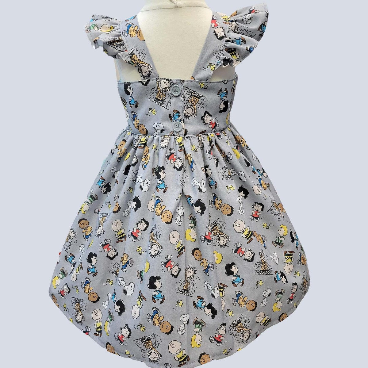 Children's dress with cartoon character pattern on a light gray background
