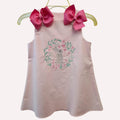 Pink sleeveless top with floral embroidery and large pink bows on a white background
