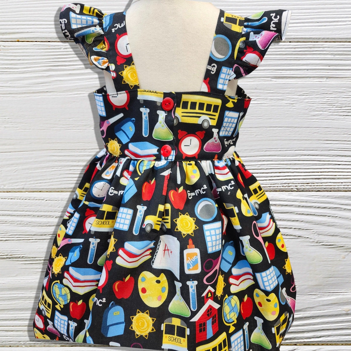 Children's dress with colorful educational pattern on a mannequin against a wooden background