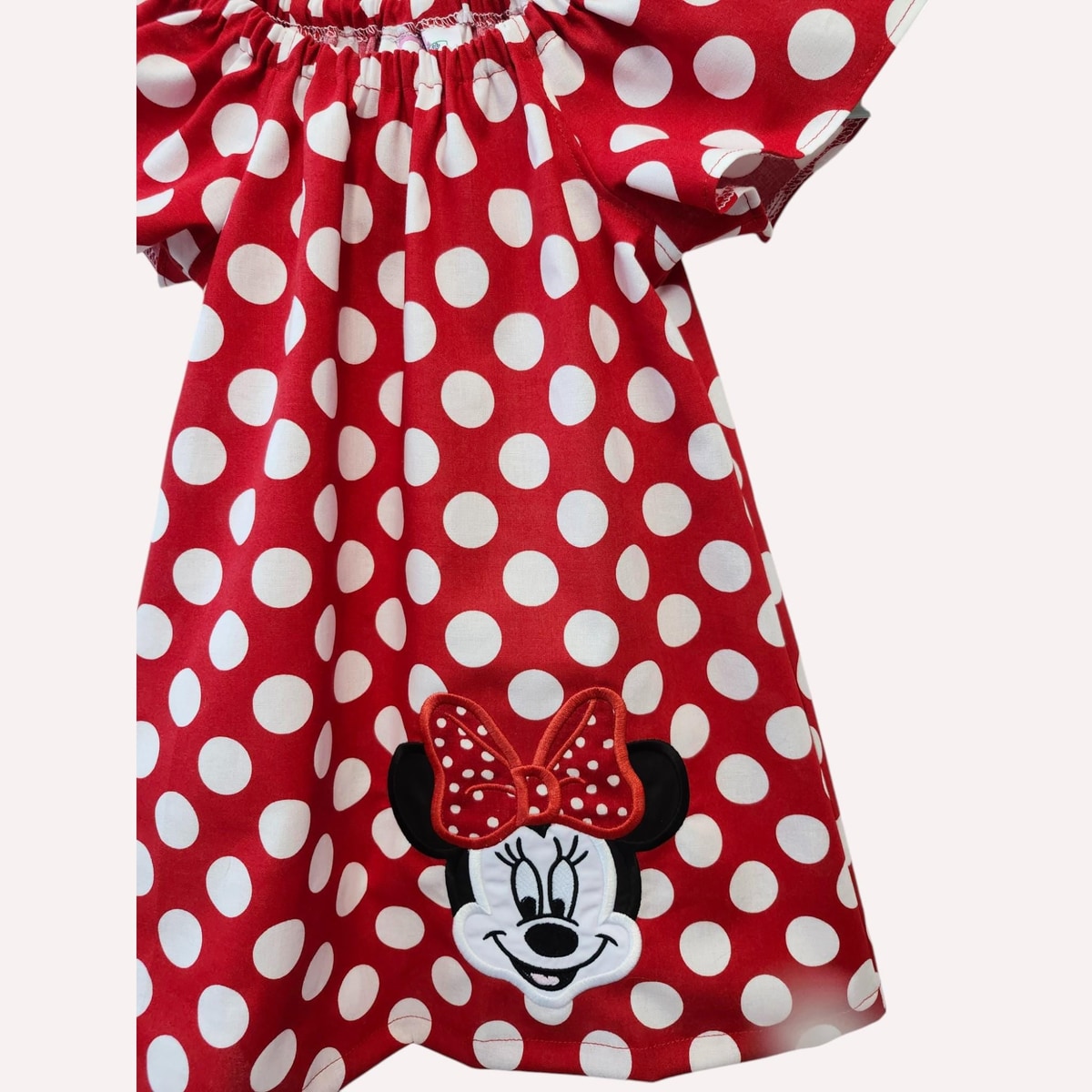 Red polka dot dress with Minnie Mouse face and bow on a white background