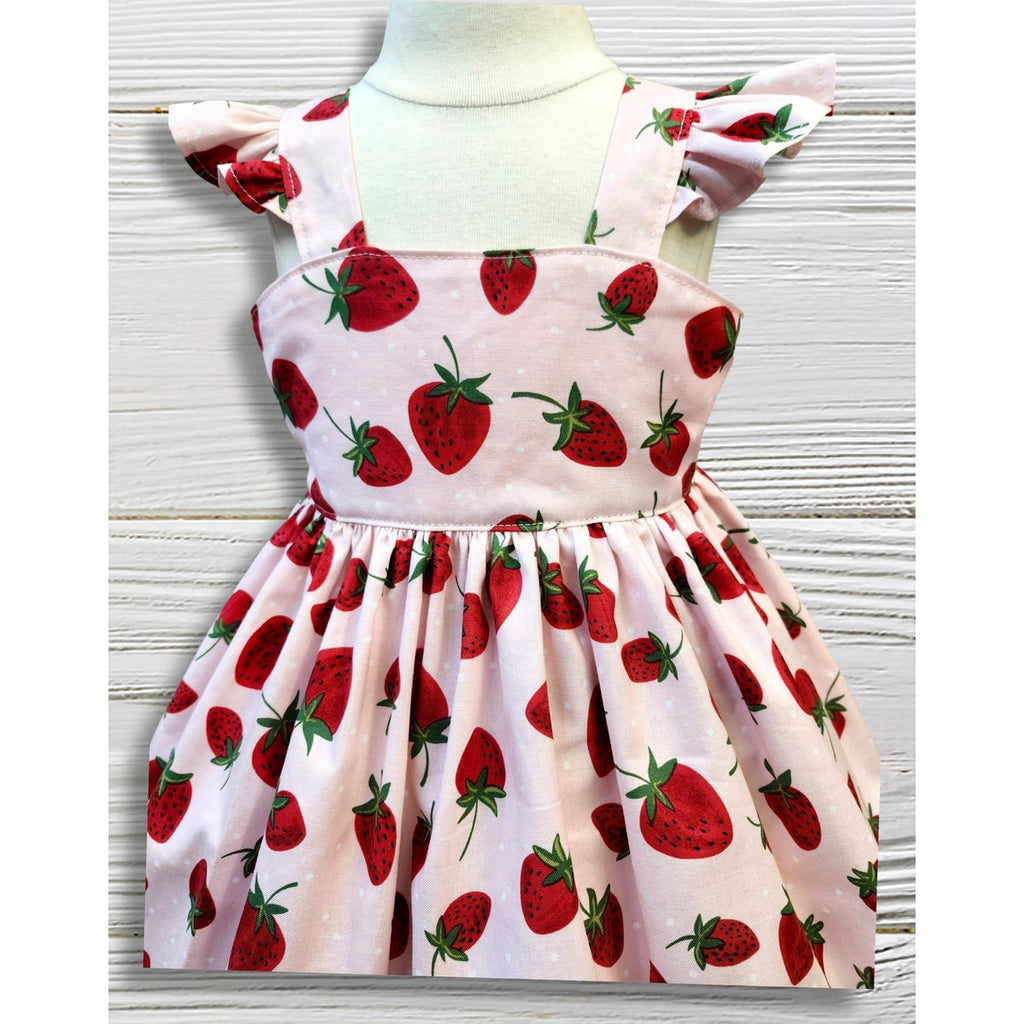 Children's dress with strawberry pattern on a mannequin against a white background