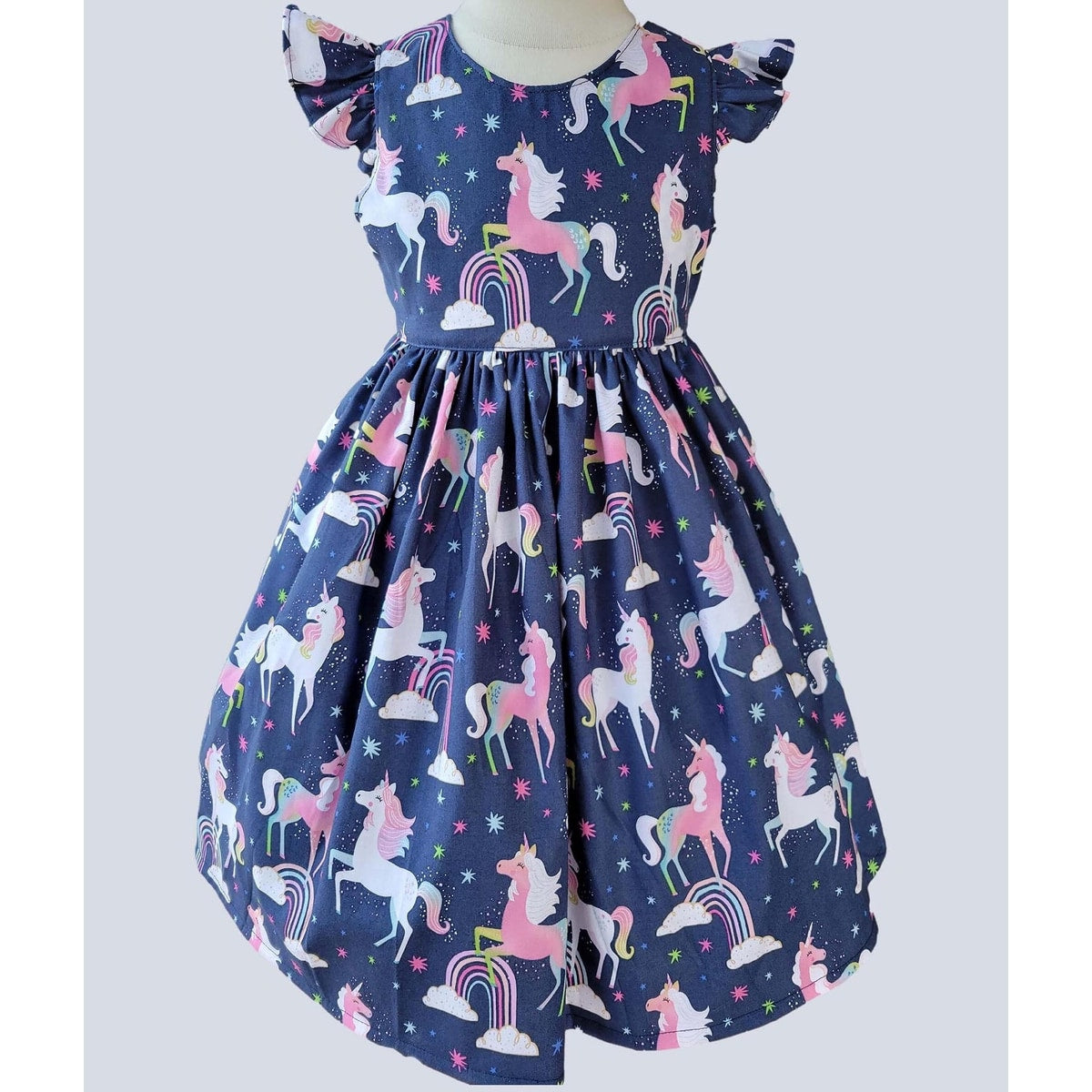 Children's dress with unicorn and rainbow pattern on a plain background