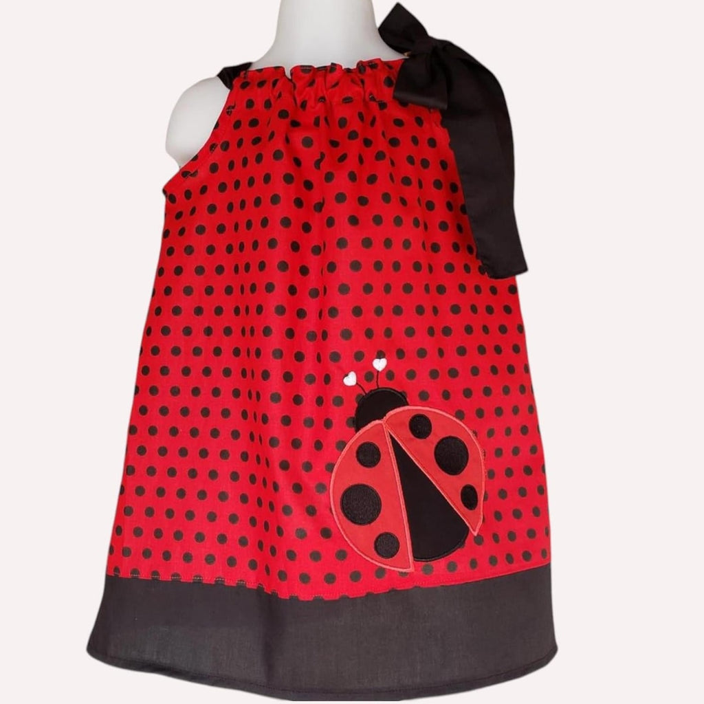 Red polka dot dress with a ladybug design on a mannequin against a white background