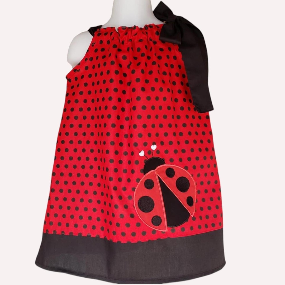 Red polka dot dress with a ladybug design on a mannequin against a white background