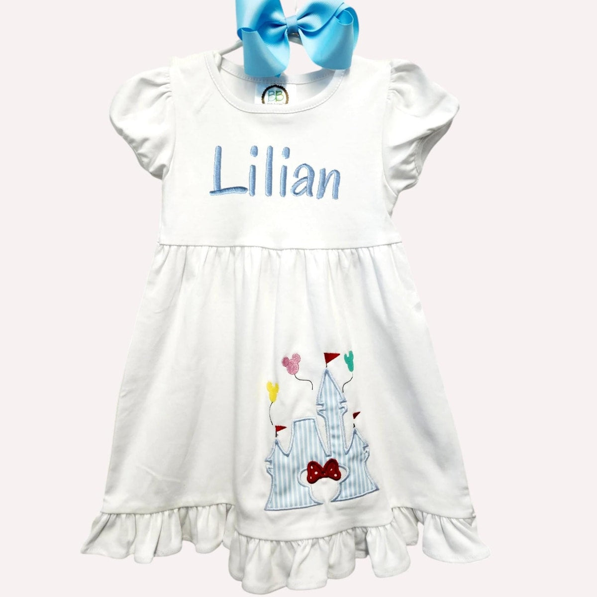 White dress with colorful design and blue bow on a white background