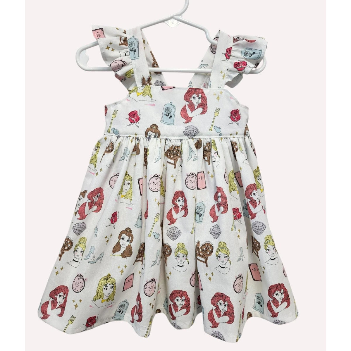 Children's dress with character print on a hanger against a white background