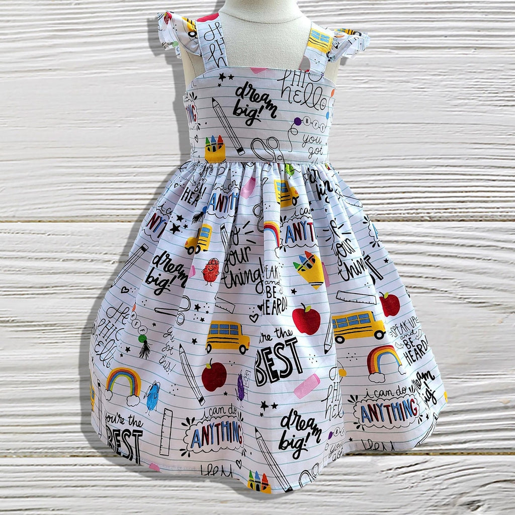 Children's dress with motivational phrases and graphics on a wooden surface