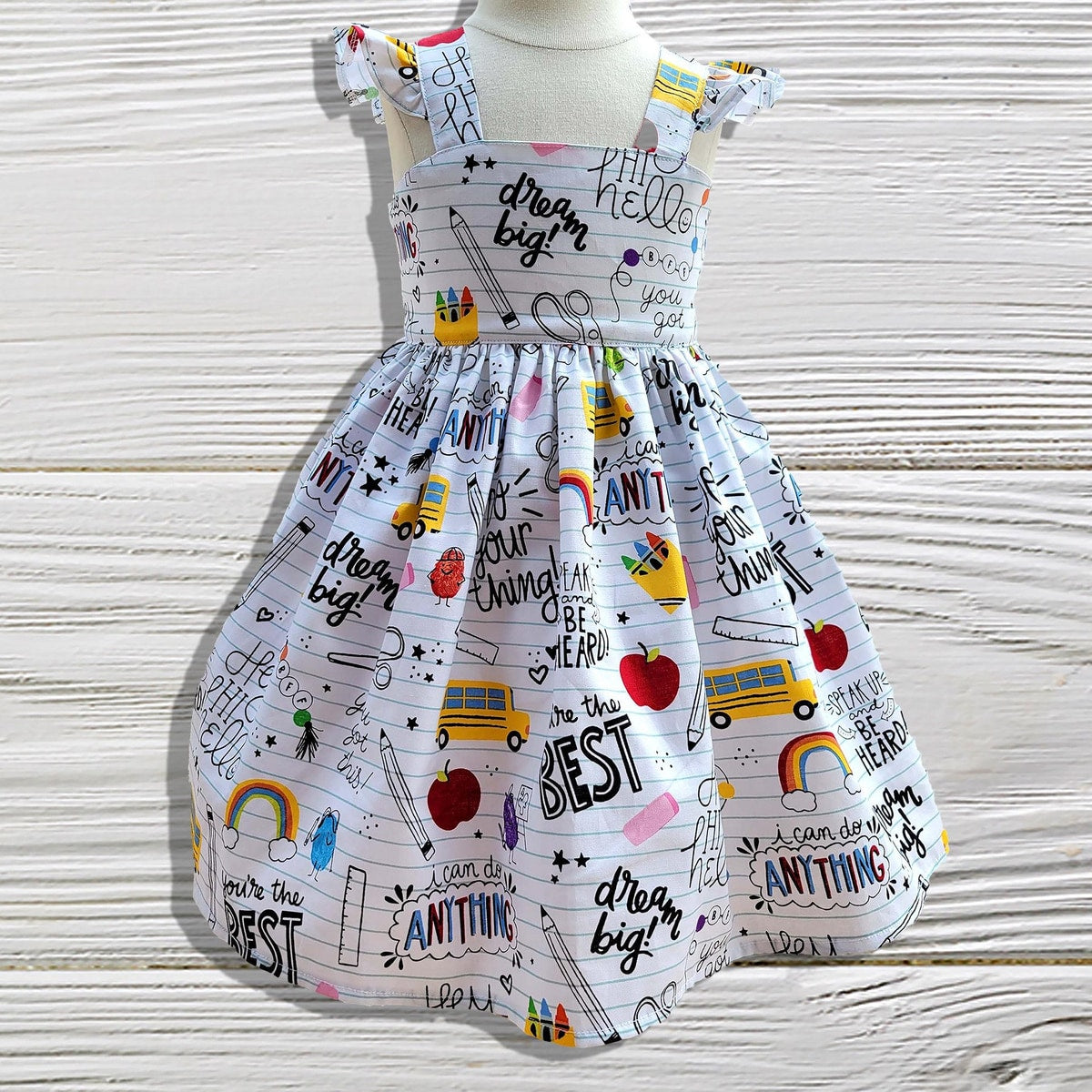 Children's dress with motivational phrases and graphics on a wooden surface
