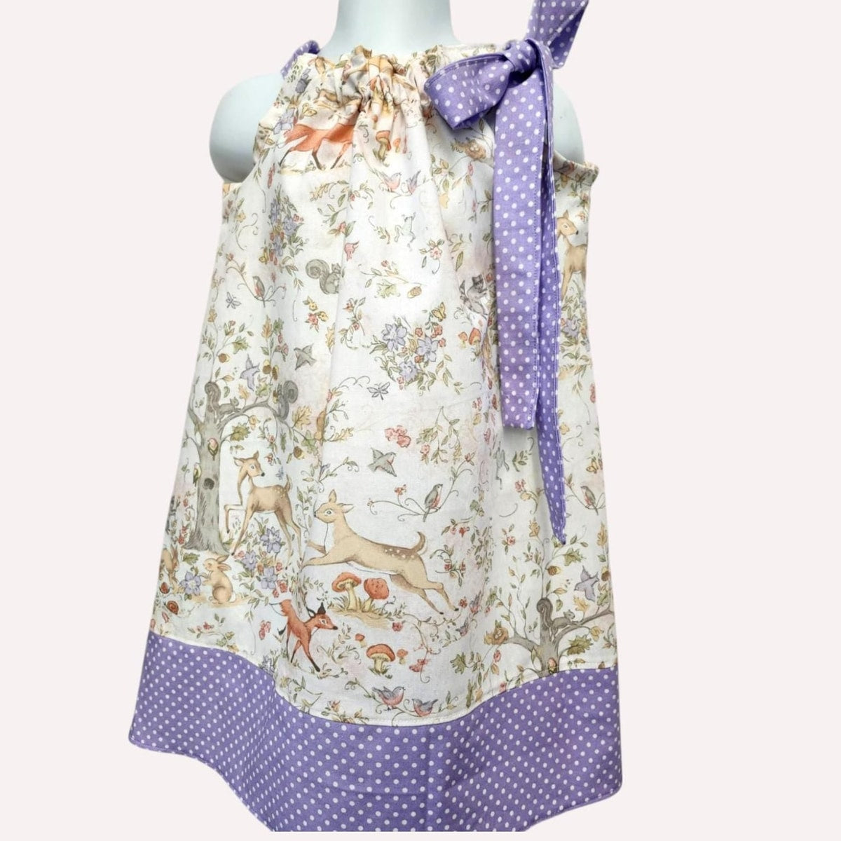 Children's dress with animal print and purple polka dot details on a mannequin against a white background.