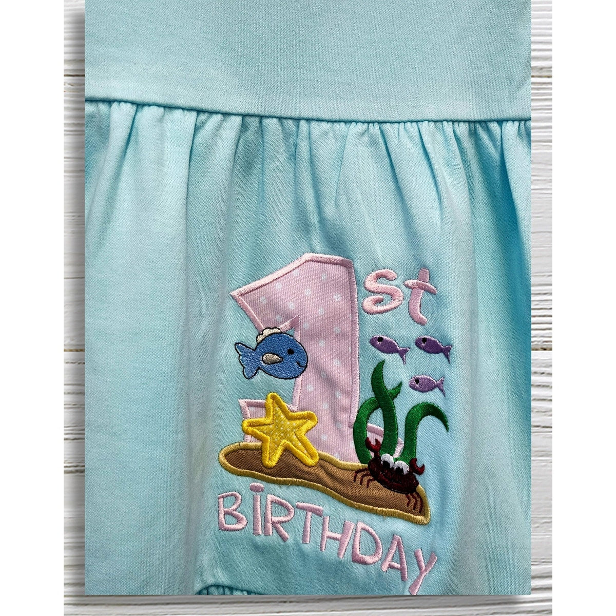 Light blue dress with '1st Birthday' and undersea-themed design on a white background
