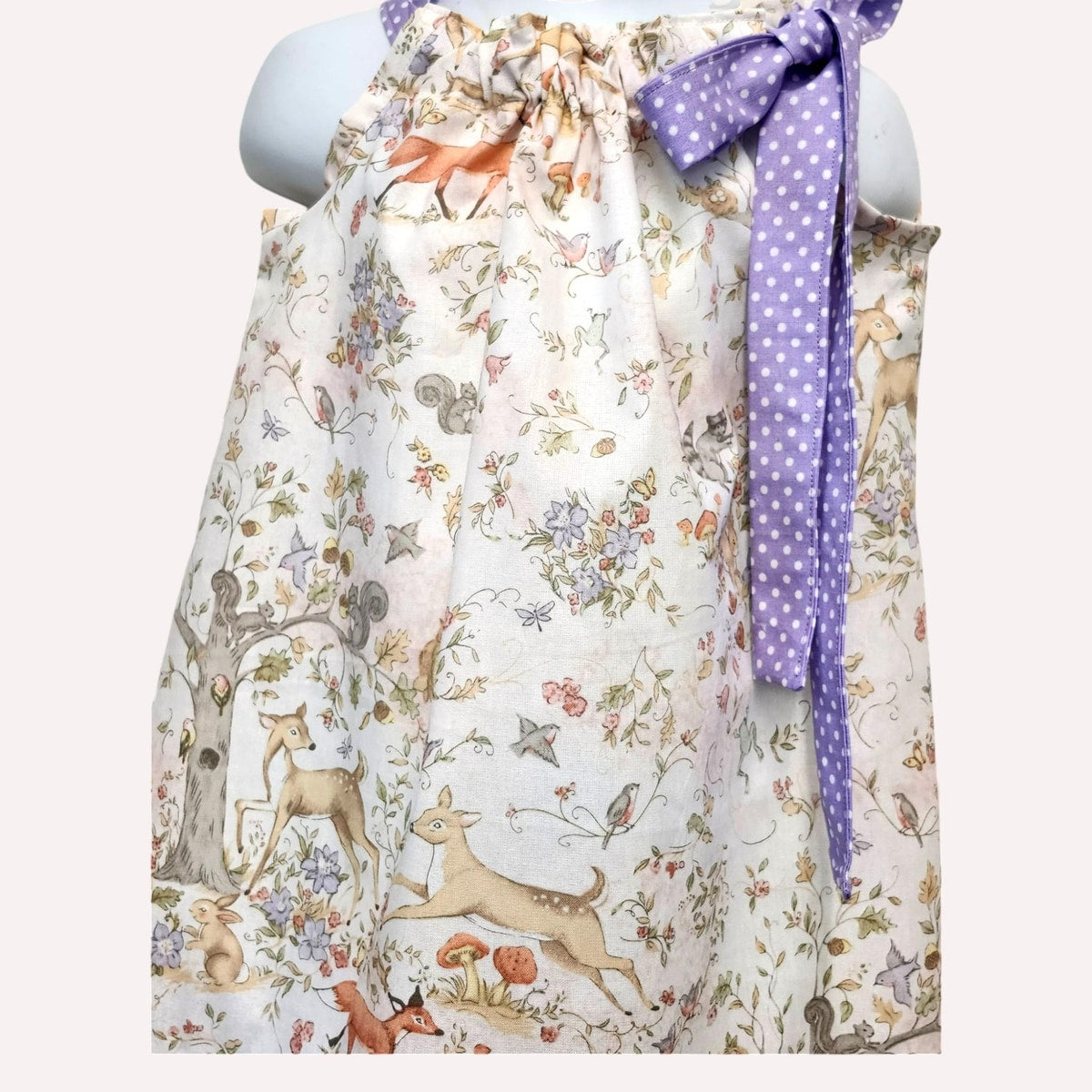 Floral apron with animal prints and a purple ribbon on a mannequin against a white background