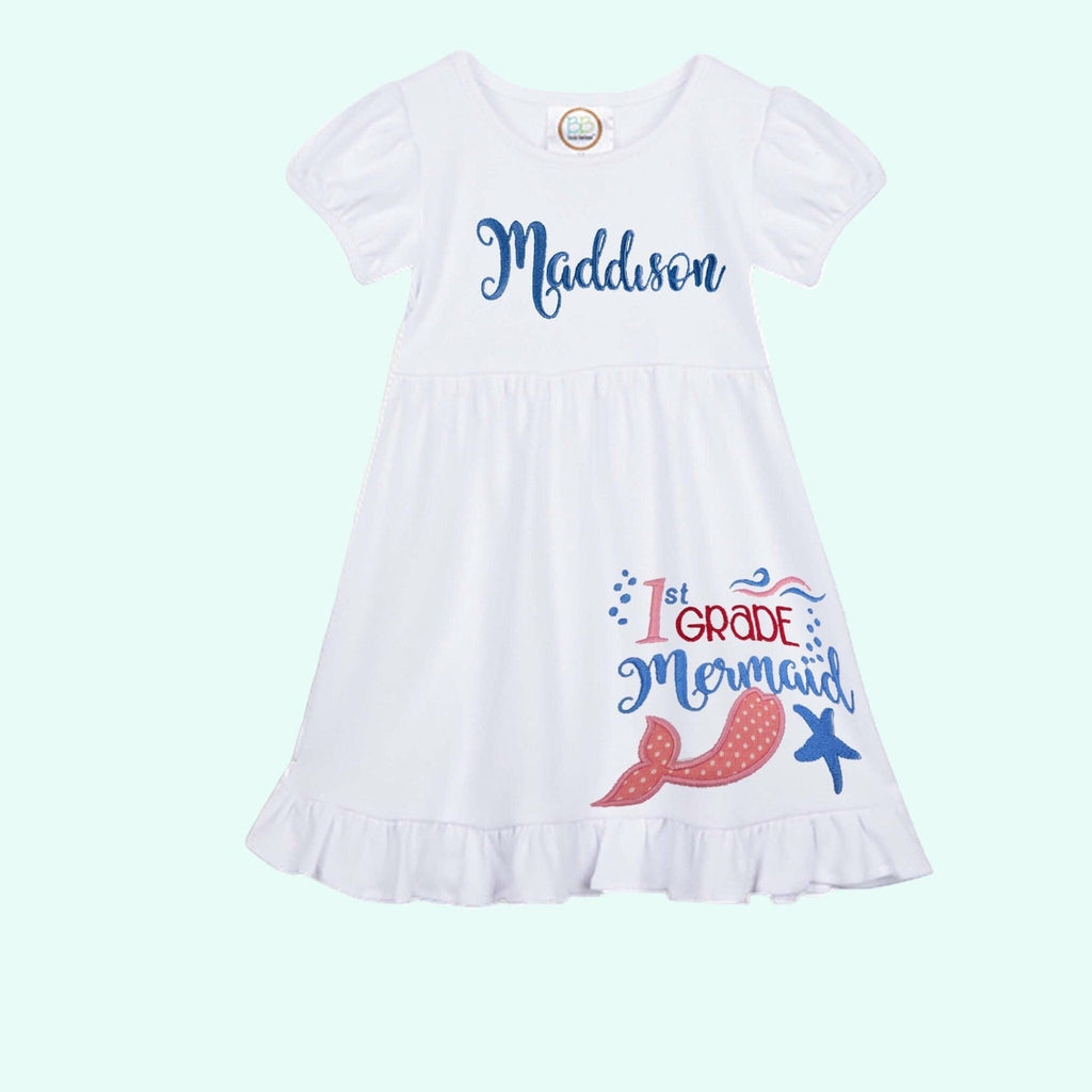 White dress with '1st Grade Mermaid' text and graphics on a light blue background