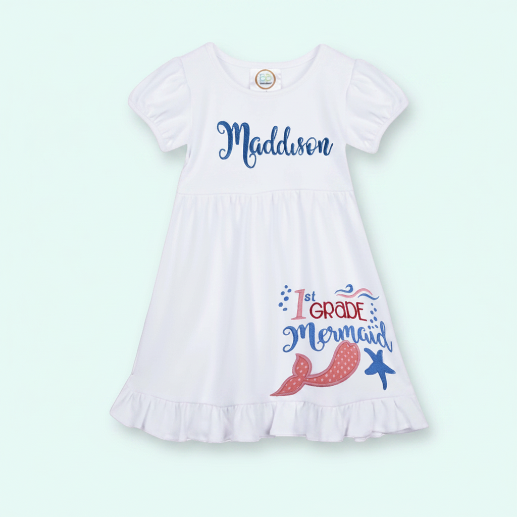 White dress with '1st Grade Mermaid' text and graphics on a light green background