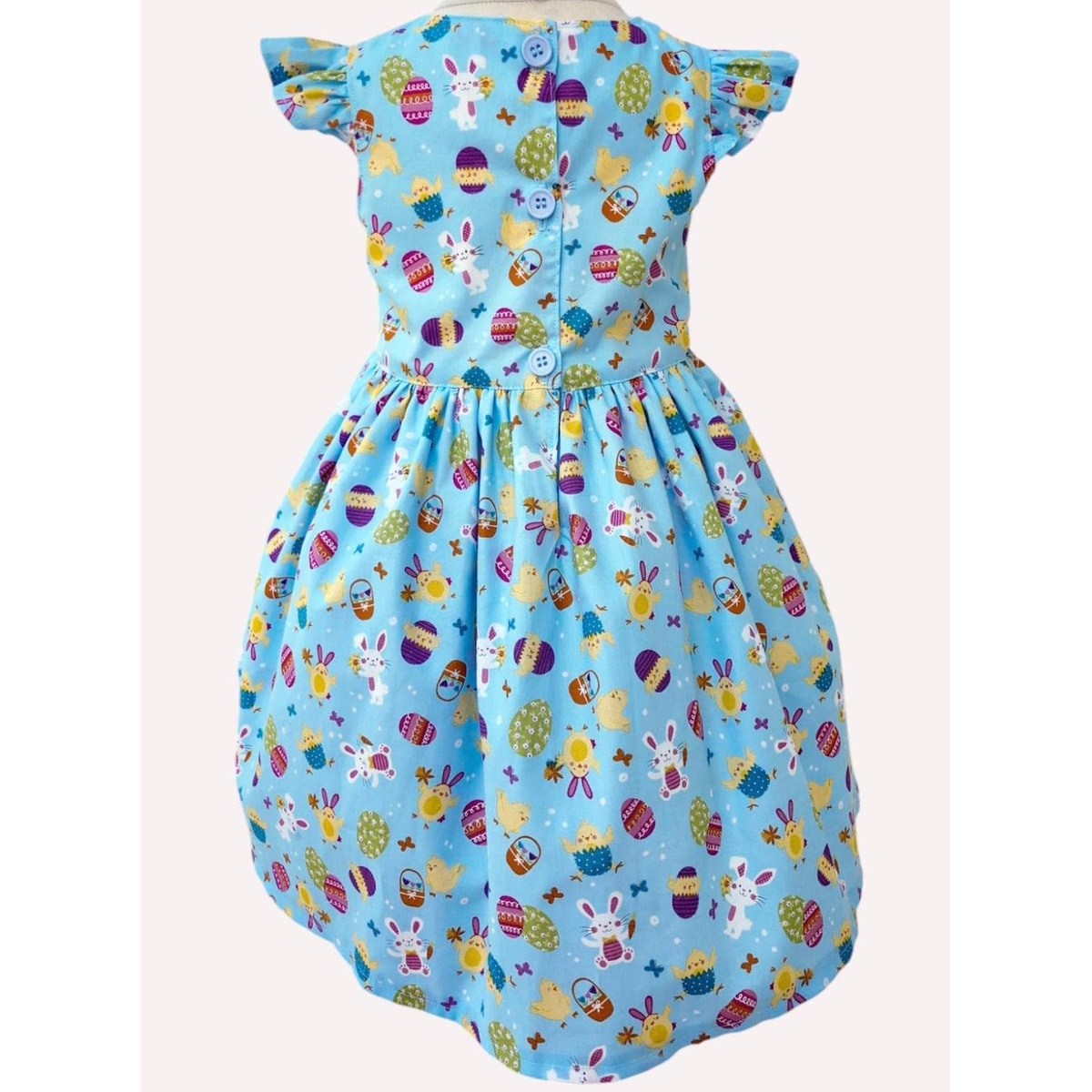 Children's dress with Easter-themed pattern on a light blue background