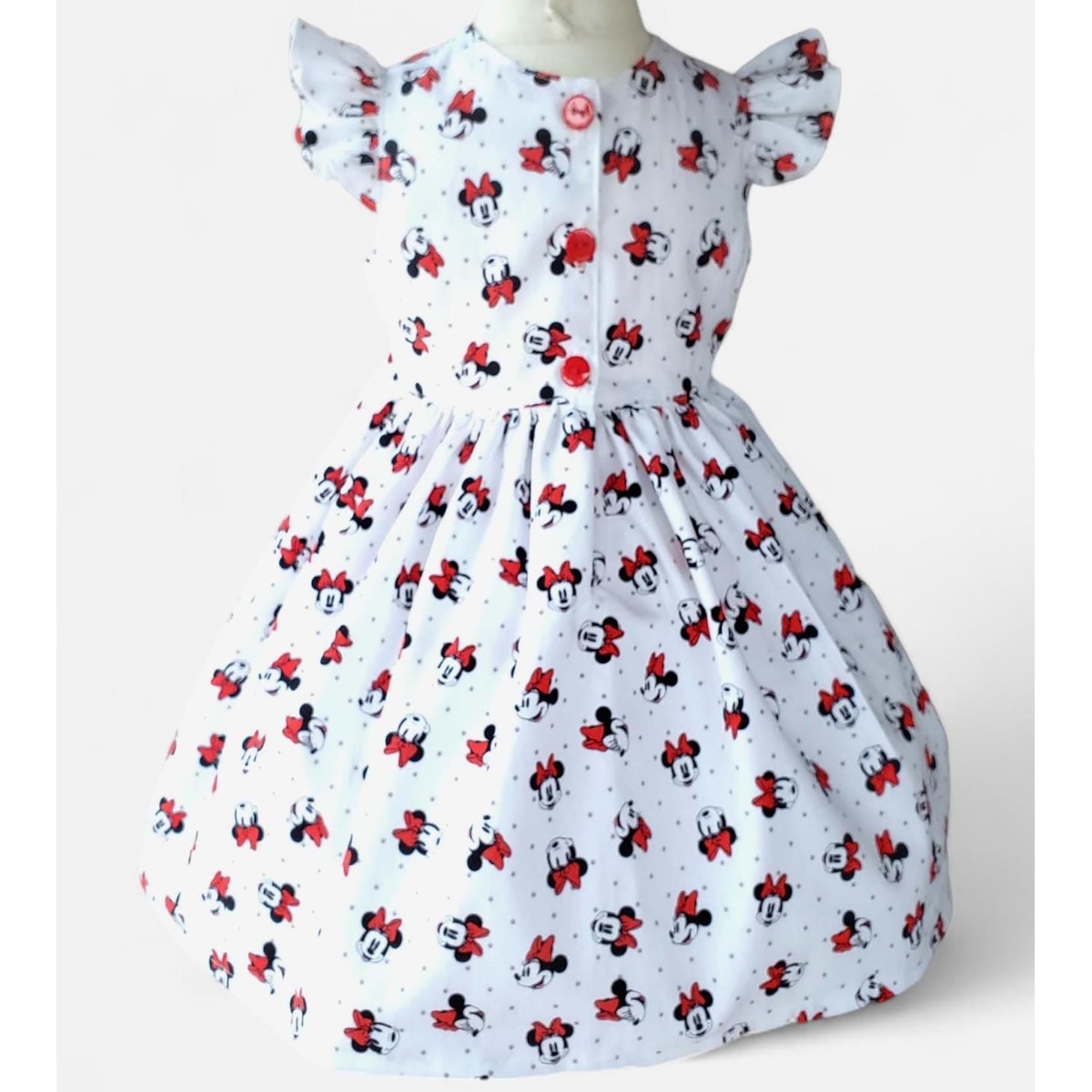White dress with red and black Minnie Mouse pattern on a white background