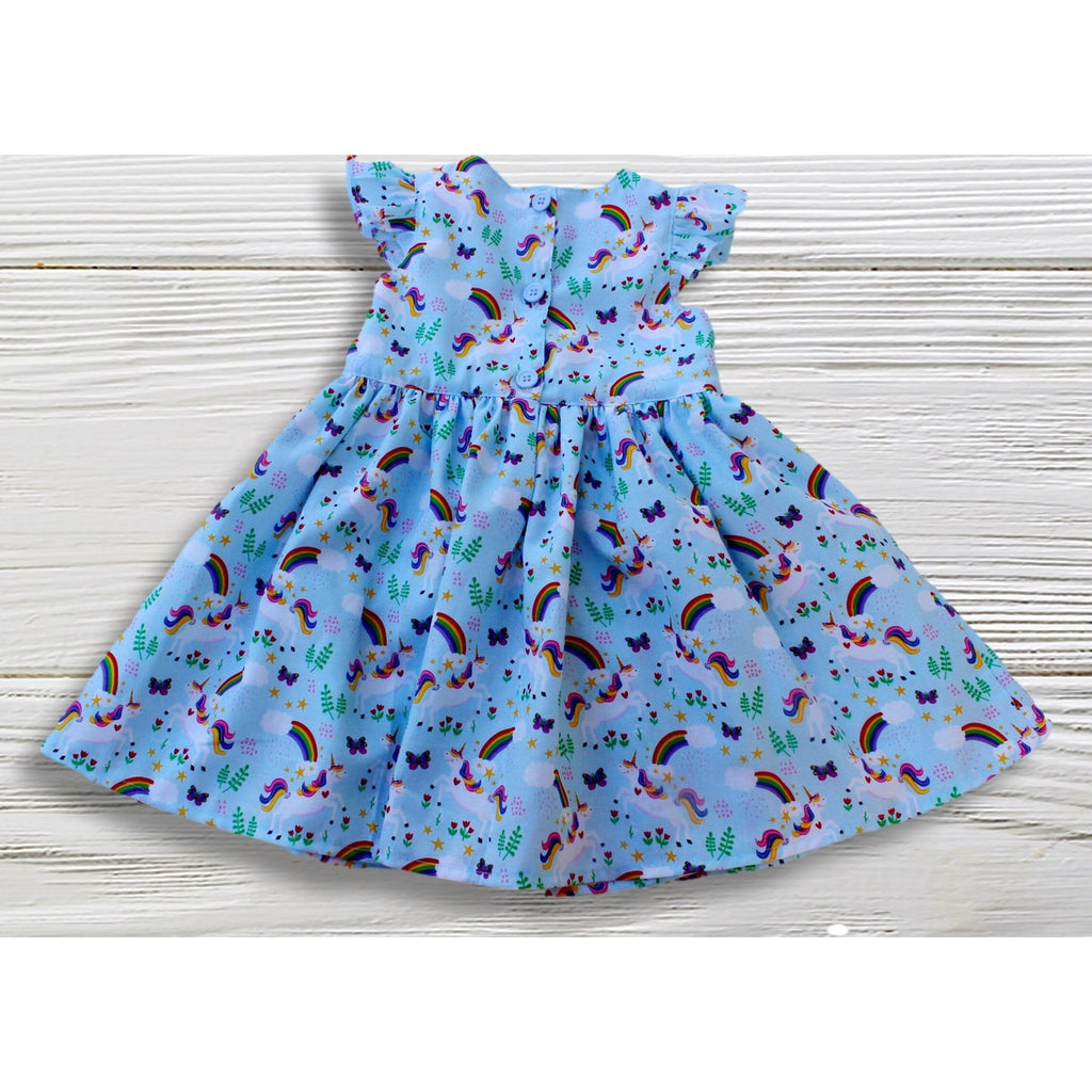 Children's dress with rainbow and unicorn pattern on a wooden surface