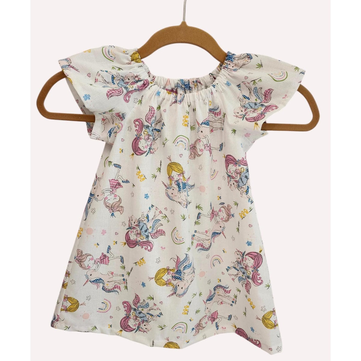 Children's dress with mermaid pattern on a hanger against a white background