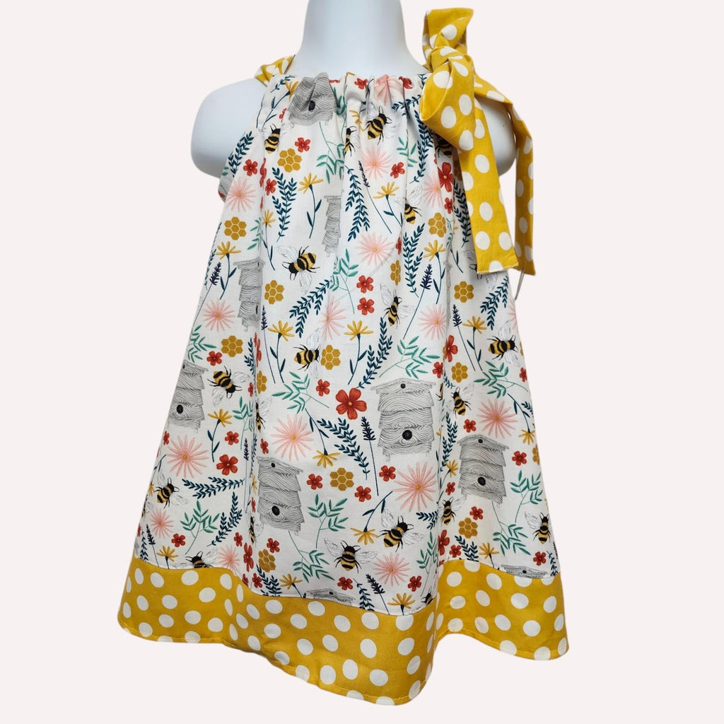 Children's dress with floral and polka dot patterns on a mannequin against a white background