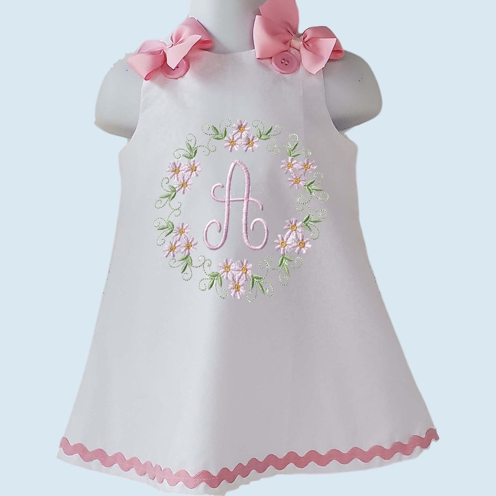 White dress with pink floral embroidery and bow accents on a light blue background