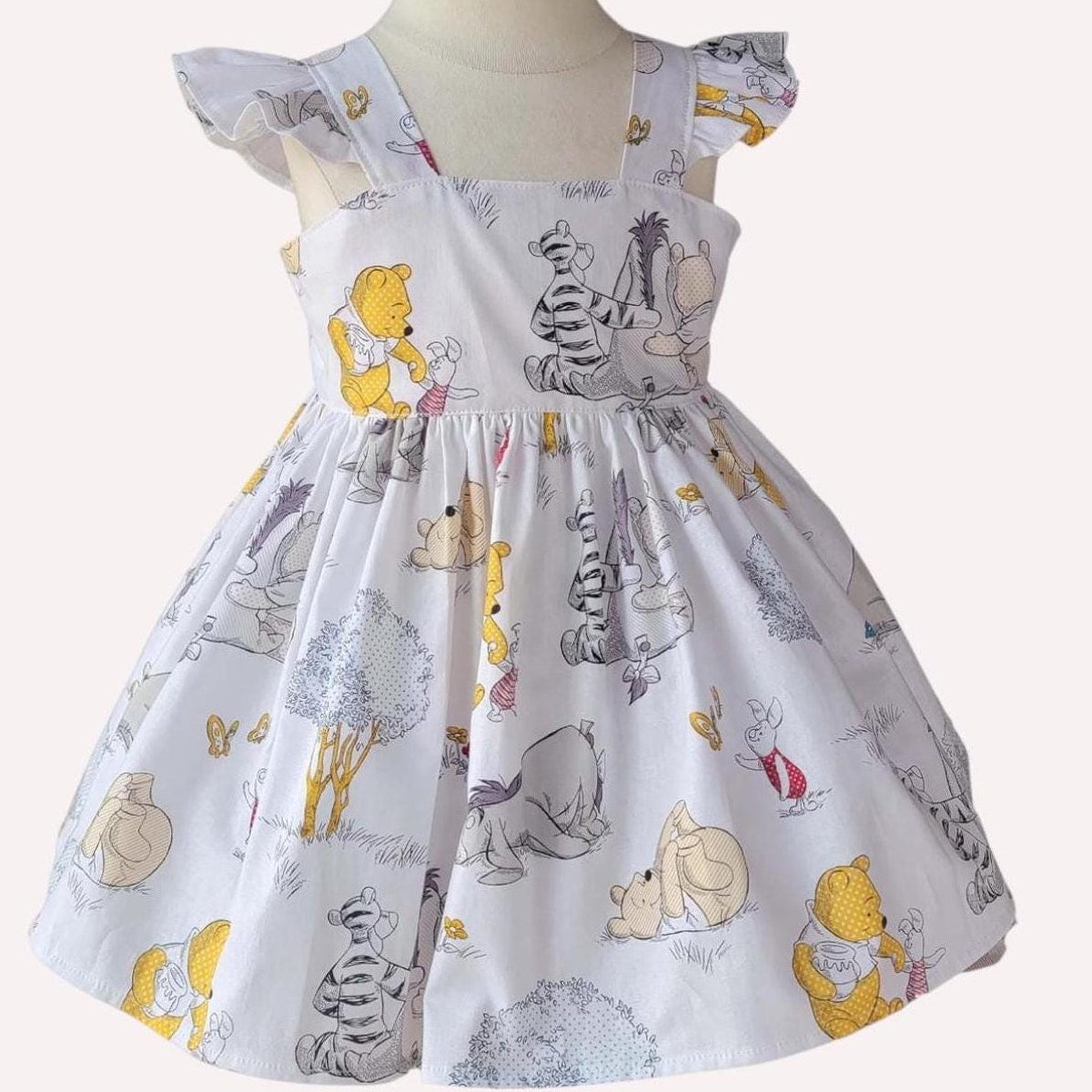 Children's dress with cartoon character print on a mannequin against a white background
