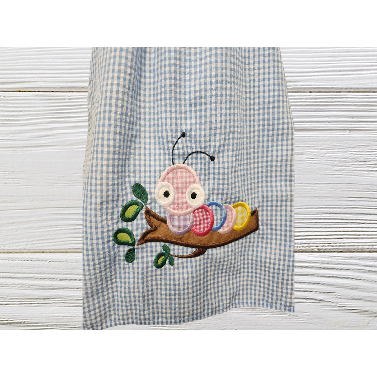 Checkered apron with a caterpillar design on a wooden surface