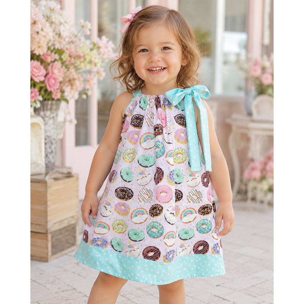 Young girl wearing a colorful dress with donut pattern outdoors.