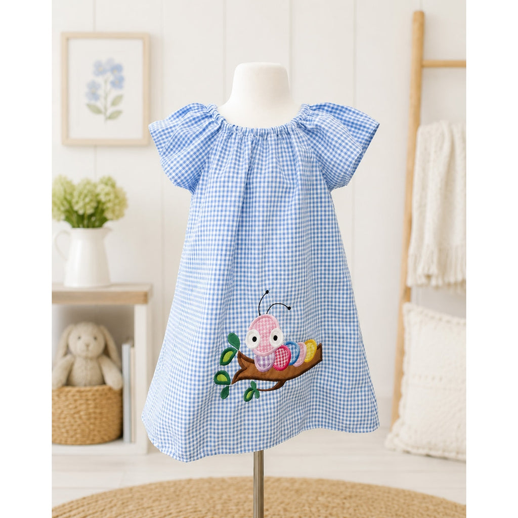 Blue checkered dress with a pink butterfly design on a mannequin against a white wall.