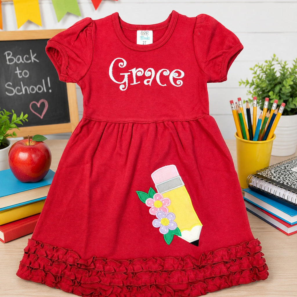 Red dress with 'Grace' printed on it, featuring a pencil design, in an educational setting.