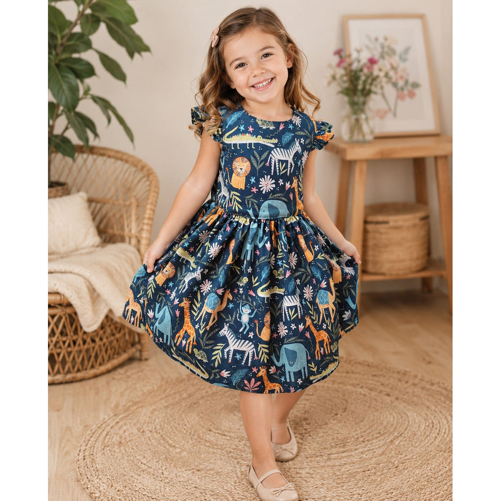 Young girl wearing a navy dress with animal print in a home setting