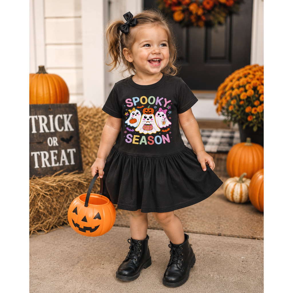 Child in a Halloween-themed black dress with pumpkins and decorations around