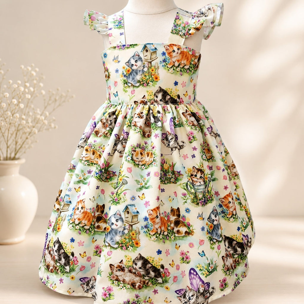 Children's dress with cat print on a mannequin against a neutral background