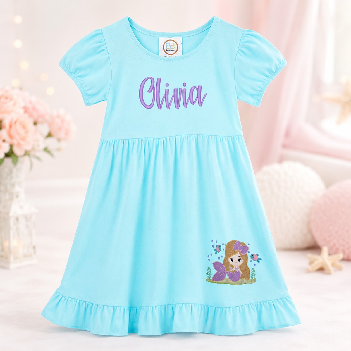 Light blue dress with a cartoon character and 'Olivia' text on a soft background